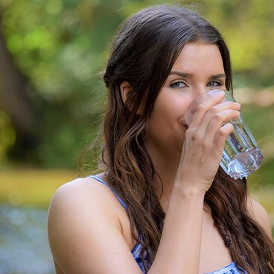 Frau trinkt ein Glas Wasser: Viel trinken hält den Mund während einer Chemotherapie feucht