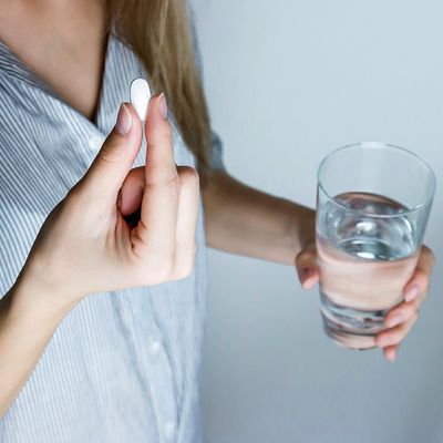 Hand mit Wasserglas und Tablette – Medikamente als Ursache für Mundtrockenheit